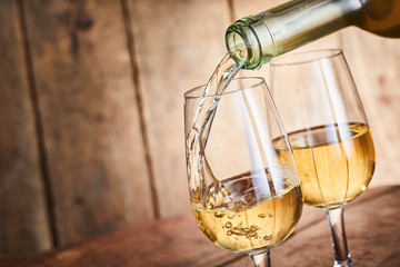 Dispensing golden white wine into two wineglasses