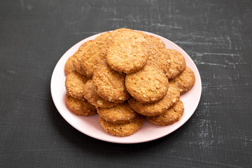 Cereal cookies on a pink plate on a black surface, side view. Closeup.