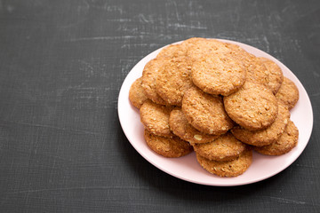 Cereal cookies on a pink plate on a black background, side view. Copy space.