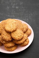 Cereal cookies on a pink plate on a black surface, side view. Copy space.