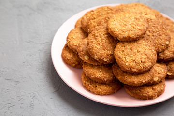 Cereal cookies on a pink plate on a concrete background, side view. Copy space.