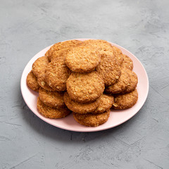 Cereal cookies on a pink plate on a concrete background, side view.