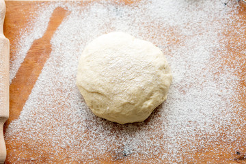 Dough with flour and rolling pin on the board. Ready, roll out the dough. Work baker. We bake rolls and pies in the kitchen