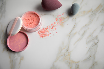Looses Rouge Puder Make-up mit Blender Schwamm auf Marmor Beauty Schminktisch