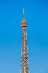 Close-up of the Eiffel Tower in Paris France  with elevators going up and down on a beautiful summer day with blue sky and white clouds