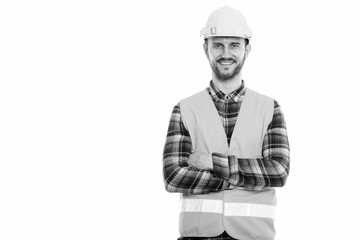 Studio shot of happy young man construction worker smiling with arms crossed
