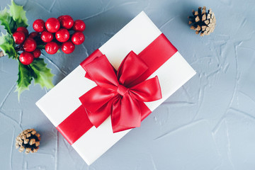 Beautiful top view of  christmas present decoration. New Year gift box decorated with red ribbon and pine tree cone. Christmas present and holy berries wallpaper.