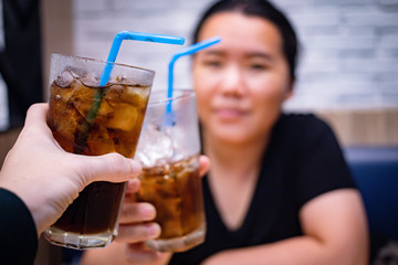 Young couple with glasses of refreshing cola with ice in restaurant, Two glasses of cola with ice
