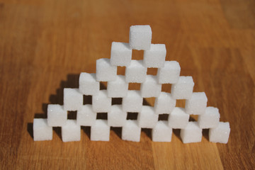 Fototapeta na wymiar high sugar pyramid built of sugar cubes, concept of excess sugar intake, diabetic, close-up, copy space