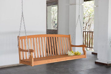 The brown wood swing in the backyard.