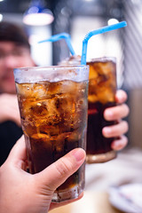 Young couple with glasses of refreshing cola with ice in restaurant, Two glasses of cola with ice