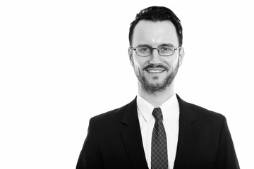 Studio shot of young happy businessman smiling while wearing eyeglasses