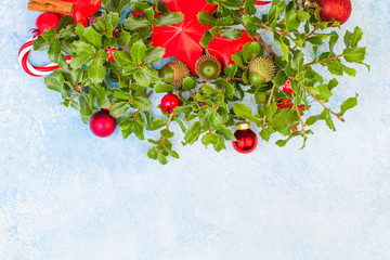 Christmas background with green holly leaves, red berries and Xmas decorations with copy sace