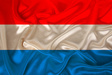beautiful photo of the Luxembourg national flag on delicate shiny silk with soft draperies, the concept of state power, country life, horizontal, close-up, copy space