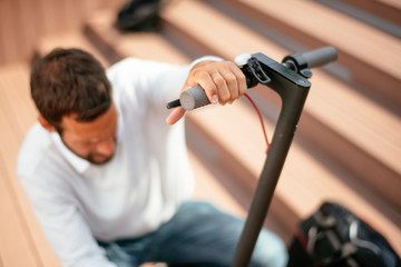 Young businessman fixing his electric scooter