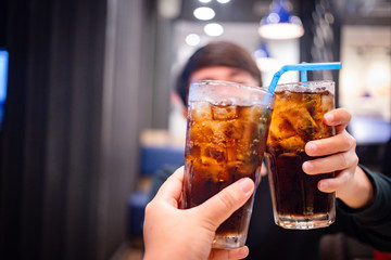 Young couple with glasses of refreshing cola with ice in restaurant, Two glasses of cola with ice