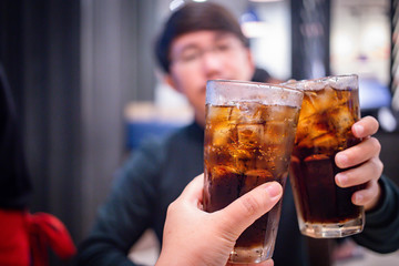 Young couple with glasses of refreshing cola with ice in restaurant, Two glasses of cola with ice