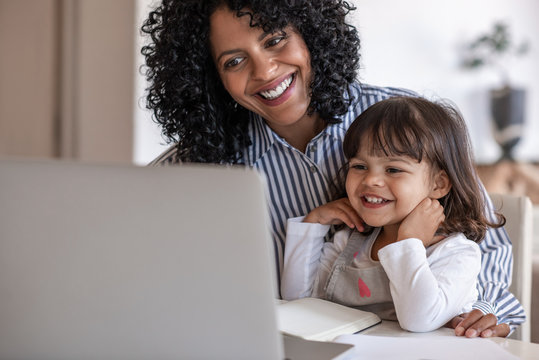 Busy mother and entrepreneur using a laptop with her daughter