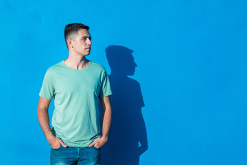 Fototapeta premium Young man standing isolated on blue background. People and emotions concept with copy space.
