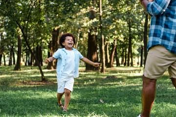 Naklejka premium happy african american kid running and looking at father