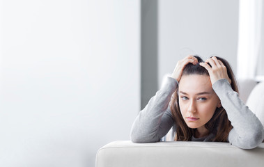 Depressed young woman on sofa at home.