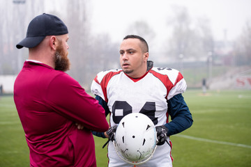 american football player discussing strategy with coach
