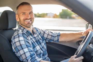 Attractive man driving a car on a clear day. Buying or renting a car.