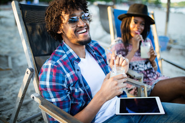 Happy couple with drinks relaxing on the beach