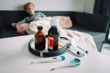 Sick child with fever at home, medicines on the table