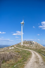 Fototapeta na wymiar View of a wind turbine on top of mountains, blue sky as background