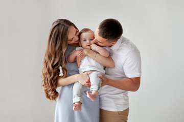 Happy young family. Beautiful Mother and father kissing their baby . Parents, Portrait of Mom, dad...