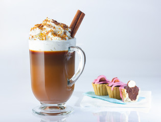 Cappuccino in a glass, Irish glass, cinnamon stick, ground nut and chocolate chips.Tartlets with chocolate paste and hazelnuts, covered with pink icing. The photo.