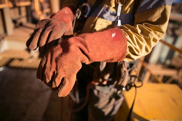 Male rope access worker welder hand preparing, wearing safety industry heavy duty reinforced...