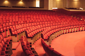 Rows of red cinema seats. View of empty theater hall. Comfort chairs in the modern theater interior