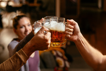 Group of happy friends drinking and toasting beer at bar 