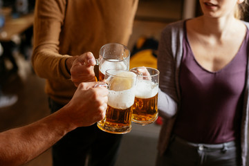 Group of happy friends drinking and toasting beer at bar 