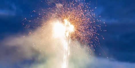 Firewoks, explosion - sparks blurred by speed. Evening sky in background.