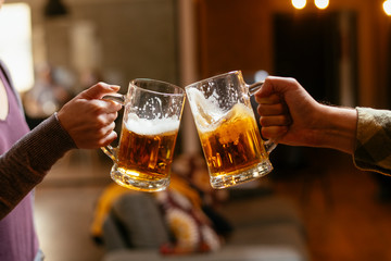Close-up of two people toasting with beer.