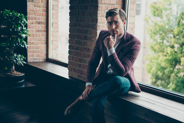 Photo of chic business guy looking clever eyes deeply thinking sitting window sill hand on chin...