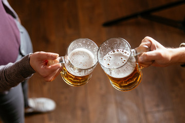 Top view of two people toasting with beer.