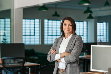 Smiling businesswoman standing by her desk in the afternoon