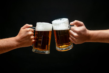 Hands toasting with beer on black background