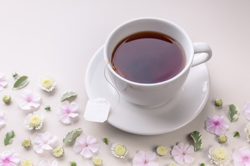 Obraz na płótnie Canvas Close-up white ceramic cup with tea on a floral pattern on a beige background. Flower tea concept. Tea bag.