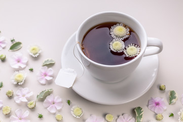 Close-up white ceramic cup with tea on a floral pattern on a beige background. Flower tea concept. Tea bag.