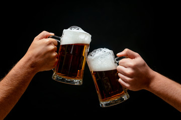 Hands toasting with beer on black background