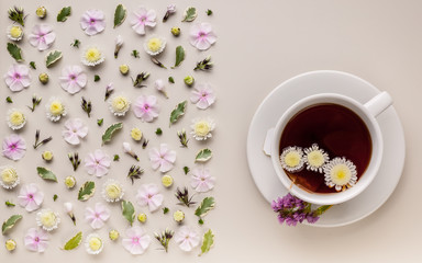 Obraz na płótnie Canvas Banner. Flavored herbal tea in a white ceramic cup with a saucer. Floral pattern on a beige background. Flower tea concept. Tea bag. Top view