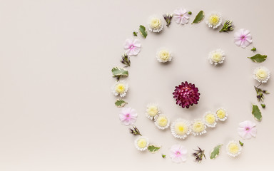 Floral smiley face on a beige background. Top view. Copy space