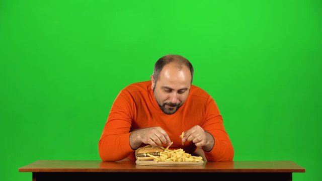 Caucasian man appearance eats french fries, then makes funy faces with her