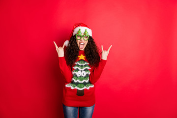 Photo of funny wavy lady chilling at x-mas rock concert show horns wear evergreen trees form specs santa hat and knitted pullover isolated red color background