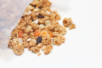 Granola with fruits and nuts in a transparent plastic bag. Baked muesli mix. Super food concept. Breakfast cereals. Kids diet. White isolation background.